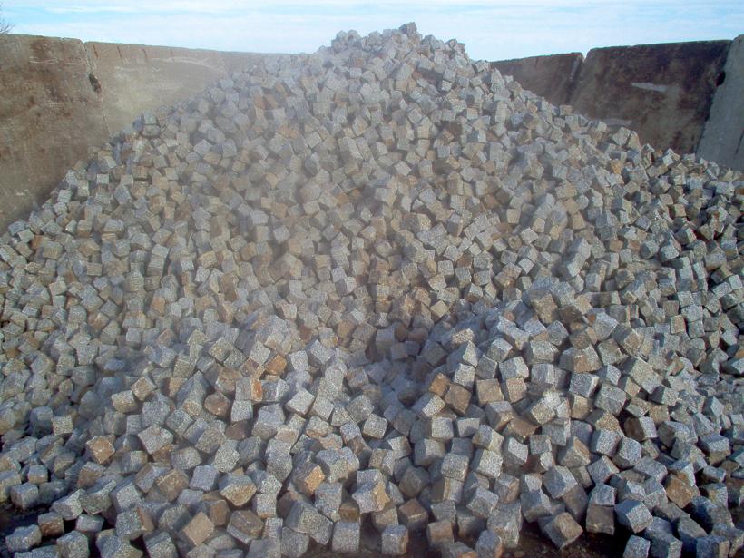 Kupa szarej kostki w kształcie sześcianów, widoczne w tle betonowe ściany